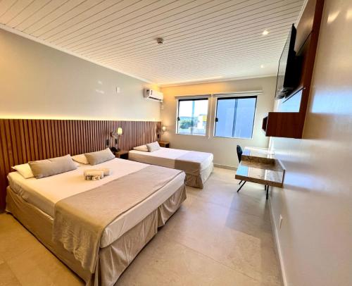 a hotel room with two beds and a television at Hotel Bons Tempos in Rio Verde