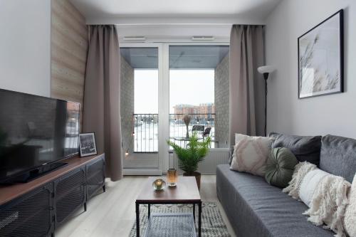 a living room with a gray couch and a television at Elite Apartments Chlebova Premium in Gdańsk