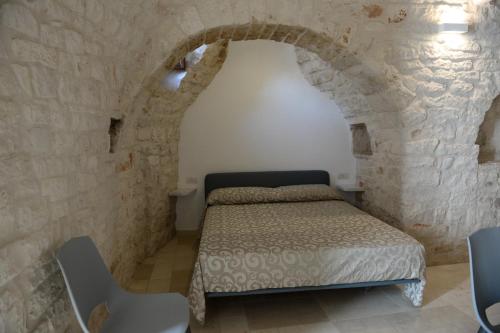 een slaapkamer met een bed in een stenen muur bij Trullo Vino & Amore in Alberobello