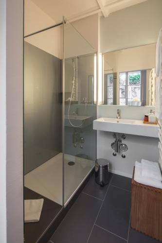 a bathroom with a glass shower and a sink at Baseltor Hotel & Restaurant in Solothurn