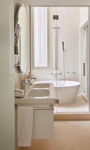a white bathroom with a tub and a sink at Palacio de los Duques Gran Meliá - The Leading Hotels of the World in Madrid