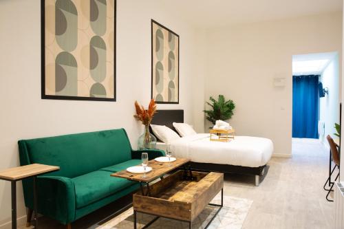 ein Wohnzimmer mit einem grünen Sofa und einem Bett in der Unterkunft NG SuiteHome - Lille I Roubaix Barbieux I Croix - Balnéo - Relax area - Netflix - Wifi - Kitchenette in Roubaix