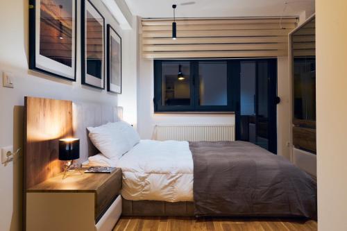 a bedroom with a bed and a table with a lamp at Cozy and Lovely Apartments I & II in Jagodina
