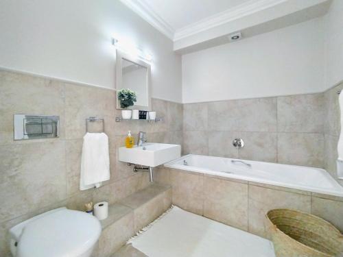 a bathroom with a tub and a toilet and a sink at Ursula's Upmarket Apartment - Panoramic Views, Large Patio - Braai, WIFI - DSTV in Plettenberg Bay