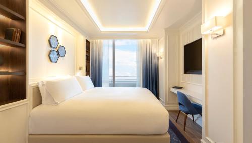 a hotel room with a white bed and a desk at Sofitel Barcelona Skipper in Barcelona
