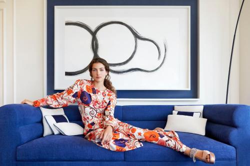 a woman is sitting on a blue couch at Sofitel Barcelona Skipper in Barcelona
