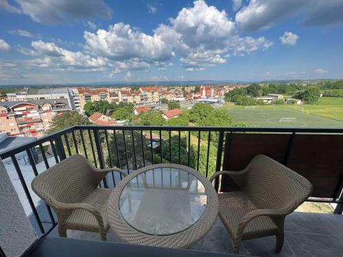 a table and chairs on a balcony with a tennis court at Cozy and Lovely Apartments I & II in Jagodina