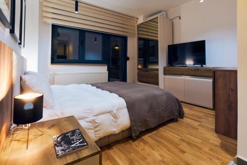 a bedroom with a bed and a television and a table at Cozy and Lovely Apartments I & II in Jagodina