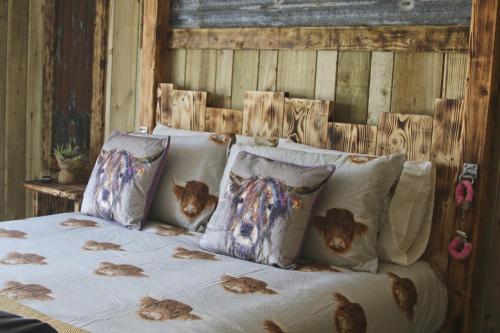 Una cama con varias almohadas con pollos. en The Moo-tel at Bargoed Farm en Aberaeron