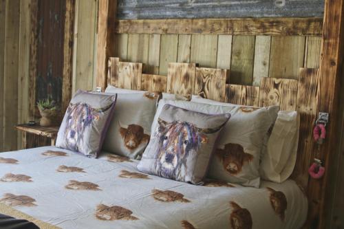 Una cama con varias almohadas con pollos. en The Moo-tel at Bargoed Farm, en Aberaeron