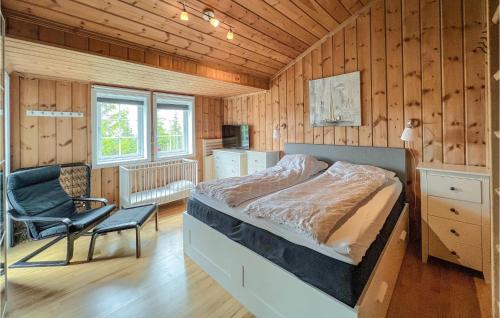 1 cama y 1 silla en una habitación con paredes de madera. en Pet Friendly Home In Sjusjen With Sauna, en Sjusjøen