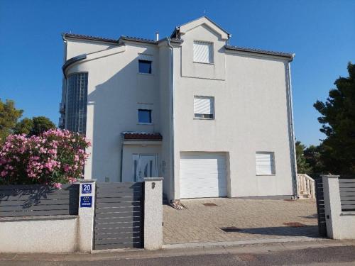 ein weißes Haus mit einem Tor davor in der Unterkunft Pinea Sol in Brodarica