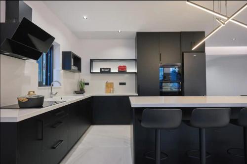 a kitchen with black cabinets and a kitchen island with bar stools at Iniohos Zante Hotel & Suites in Argasi