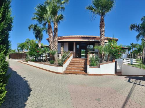 une maison avec des palmiers devant elle dans l'établissement Residence Hydria, à Campofelice di Roccella