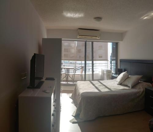 Un dormitorio con una cama y un televisor y un balcón. en Edificio Go Pocitos, en Montevideo