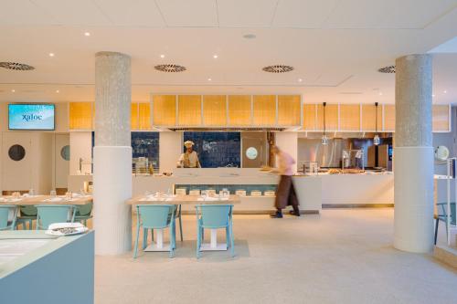 a man walking in a kitchen with a table and chairs at Blaumar Hotel in Salou