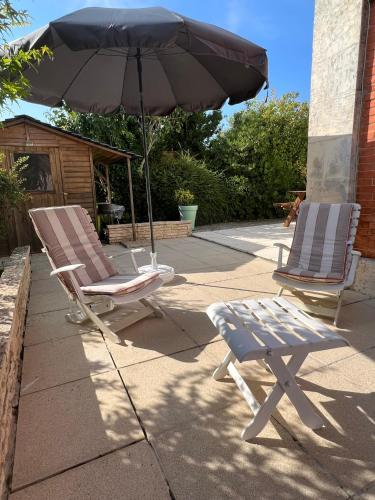 2 chaises longues et un parasol sur le trottoir dans l'établissement La Petite Angerienne, à Saint-Jean-dʼAngély