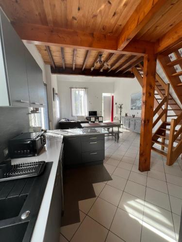 Il comprend une cuisine avec des plafonds en bois et une table. dans l'établissement La Petite Angerienne, à Saint-Jean-dʼAngély