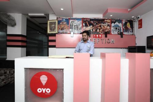 a man standing at a counter in a room with pink at Capital O Hotel Orchid Inn in Kankhal