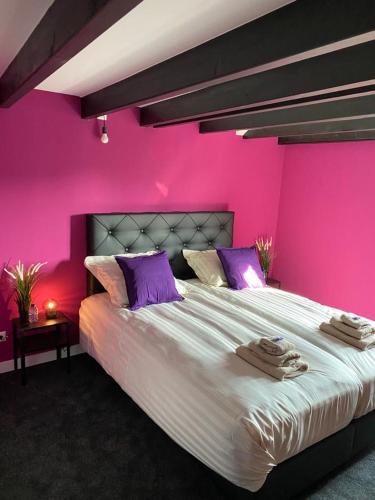 um quarto rosa com uma cama grande e toalhas em B&B with or without Schutter 7 em Zierikzee