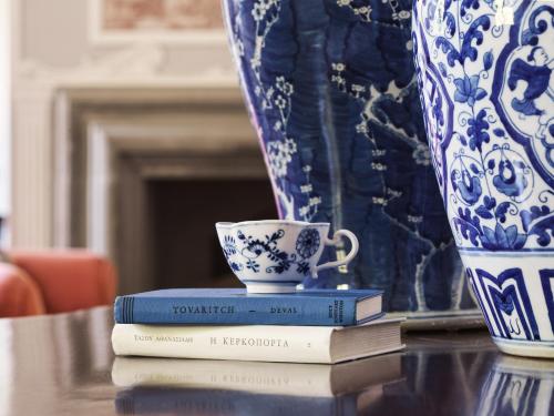 a stack of books with a cup and a vase at Villa di Piazzano - Small Luxury Hotels of the World in Cortona