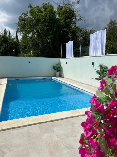 a swimming pool with blue water and purple flowers at Villa Draga in Mostar