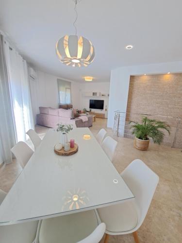 a dining room with a white table and white chairs at Villa Las Tres J in Málaga