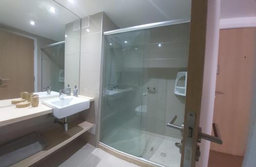 Un baño con ducha de cristal y lavabo. en Edificio Go Pocitos, en Montevideo
