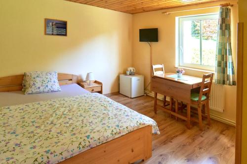 a bedroom with a bed and a desk and a window at Chata Harmonie in Bedřichov