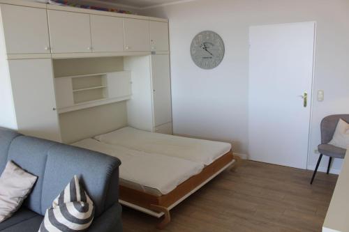 um quarto com uma cama, um sofá e um relógio em BTSD59302-FeWo-Stranddistel-IV em Burgtiefe auf Fehmarn 