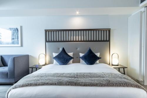 a bedroom with a large bed with blue pillows at The Vale Niseko in Kutchan