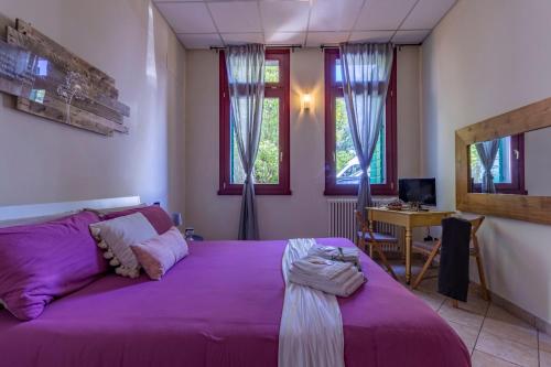 Schlafzimmer mit einem lila Bett, einem Schreibtisch und Fenstern in der Unterkunft Casa Charleston in Palazzo Nobiliare al Duomo in Padua