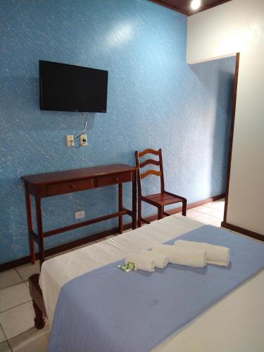 a bedroom with a bed with a desk and a tv at Pousada Albamar Guarujá in Guarujá