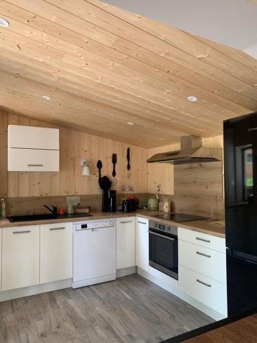 uma cozinha com armários brancos e um tecto de madeira em La Petite Auberge Insolite em Saint-Affrique