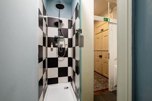 a bathroom with a shower with a checkered wall at LR Guest House in Lisbon