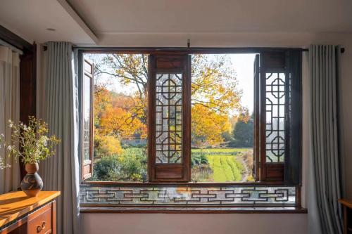 a large window with a view of a garden at Alina Garden Boutique Resort Huangshan Hongcun in Huangshan Scenic Area