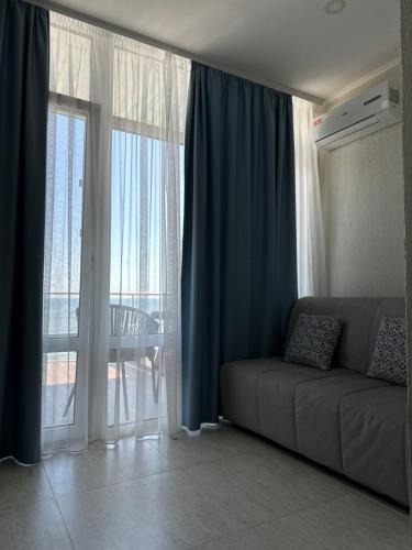 a living room with a couch in front of a window at Apart-Hotel Poseidon in Odesa
