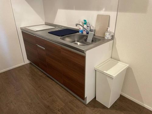 a kitchen with a sink and a trash can at 箱根湯本から一駅。大正〜昭和の家具に囲まれた、緑香るウッドテラスのある宿。高台から小田原の街を一望　 in Odawara