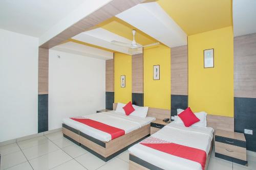 - 2 lits dans une chambre de couleur jaune et rouge dans l'établissement OYO 8501 ABHIMAANI COMFORTS, à Bangalore