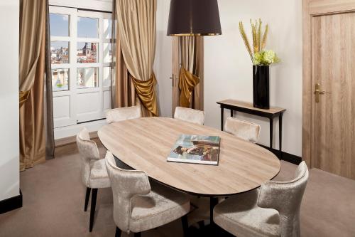 a dining room with a wooden table and chairs at Palacio de los Duques Gran Meliá - The Leading Hotels of the World in Madrid