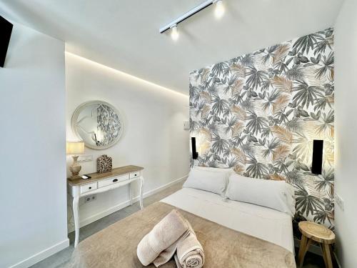 a bedroom with a white bed and a wall with palm leaves at Loft 18 Beachfront Marbella Center in Marbella