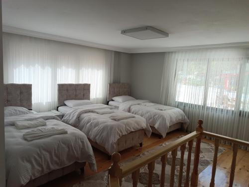 3 łóżka w pokoju z białymi ścianami i oknami w obiekcie Uzungöl-Daire-Apart-Kiralık w mieście Çaykara