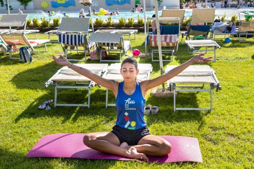 a woman sitting on a yoga mat in the grass at Fabulous village in Casal Palocco