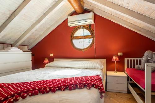 a bedroom with a red wall with a bed and a window at Sailor House Near Lake in Pianello Del Lario