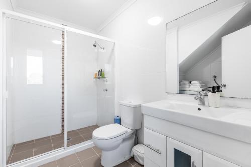 a white bathroom with a toilet and a sink at Waterview gem in Belmont