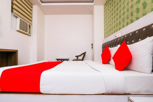 Un dormitorio con una cama roja y blanca con almohadas rojas en OYO Hotel Sehej Continental, en Nueva Delhi