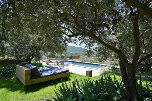 a couch sitting under a tree next to a pool at Le Pavadou B&B in Méthamis