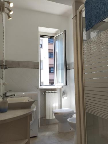 a bathroom with a toilet and a sink and a window at MI CASA TU CASA in Civitavecchia