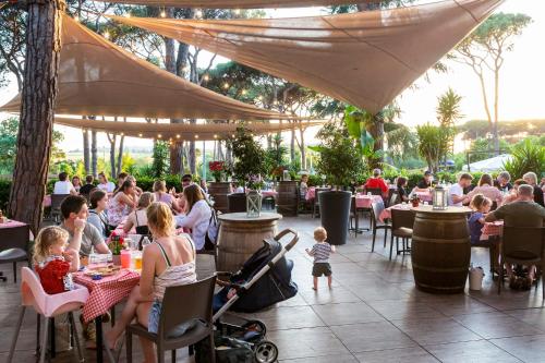 a group of people sitting at tables in a restaurant at Fabulous village in Casal Palocco