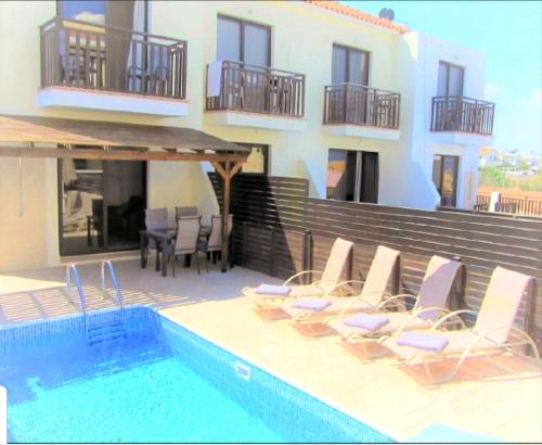 a group of chairs sitting next to a swimming pool at Villa Jade in Paralimni